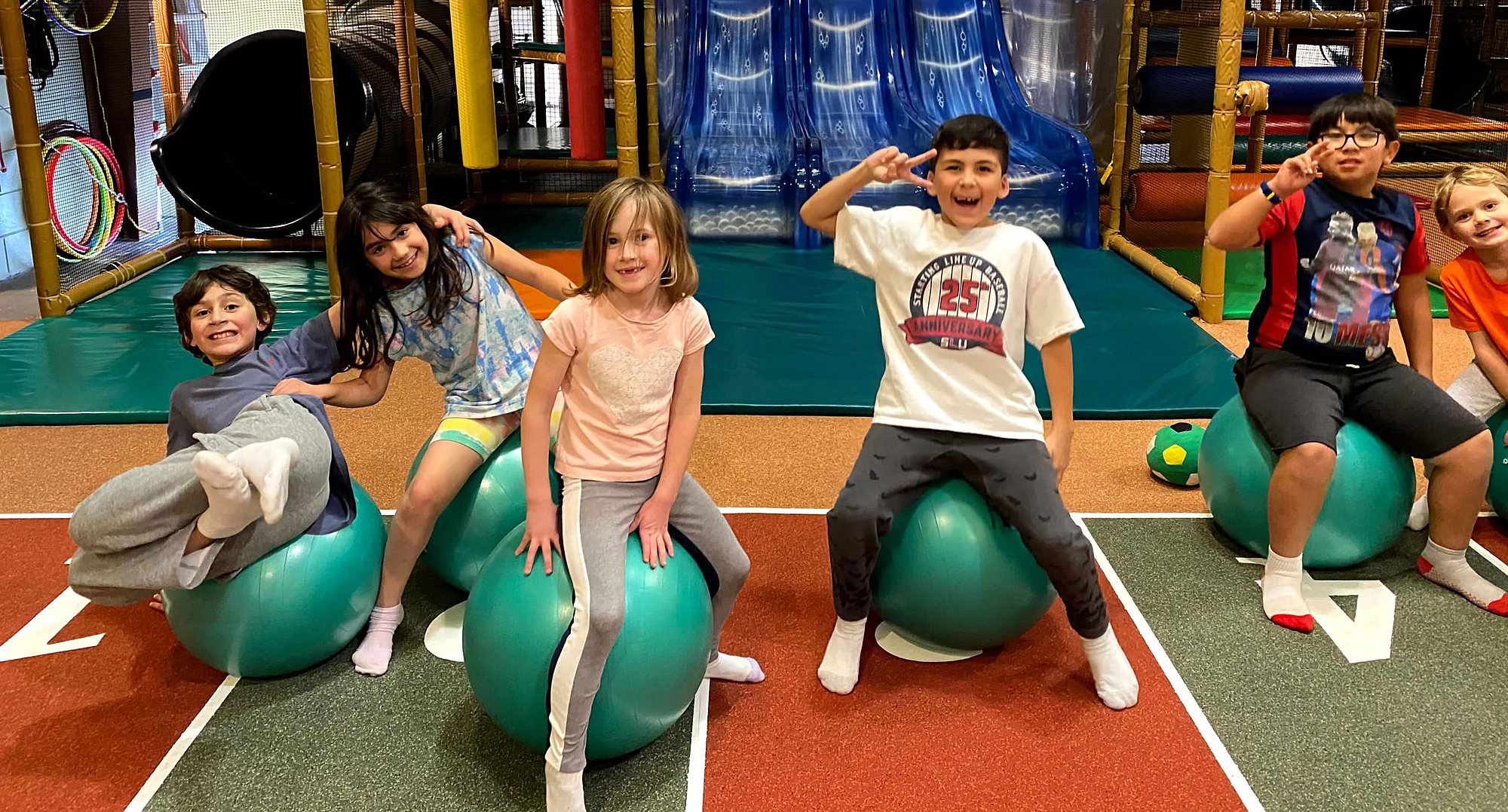 Kids smiling on stability balls in a fitness class at Safari Run